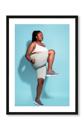Curvy sportswoman exercising against blue background