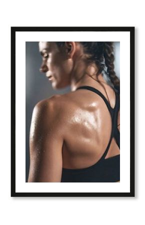 close-up shot of a sweaty woman's back and shoulder, showcasing her hard workout in the gym