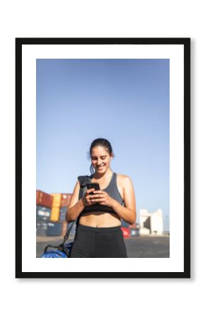 Woman in sportswear looking at phone in sunlight