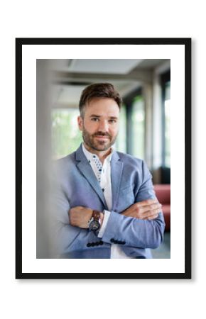 Smiling businessman in blazer with arms crossed at modern office