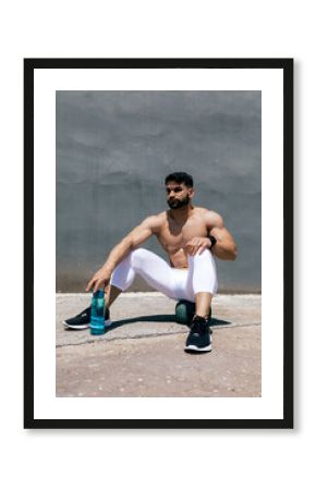 Fit man resting after workout with water bottle
