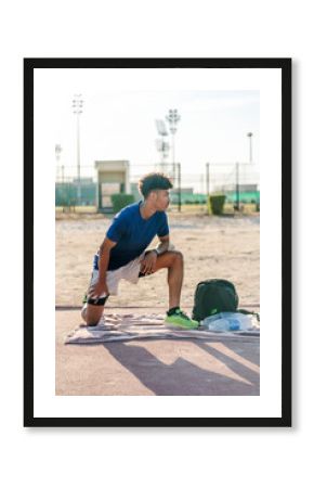 Young athlete stretching legs on running track in Oman