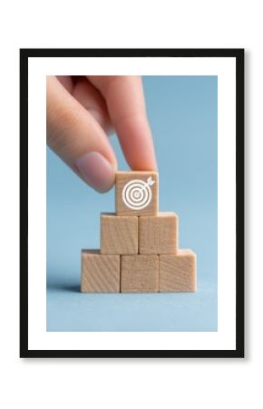 person's hand, success, achievement, goal, profit, performance, strategy, Completing the Puzzle of Success: Hand Placing Final Wooden Block with Target Icon on Blue Background