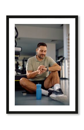 Male athlete using smart watch on break in health club.