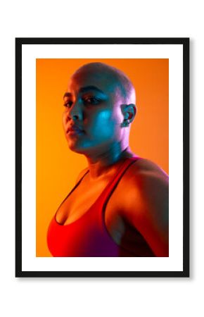 Bald athlete in sportswear with serious expression in colorful lighting