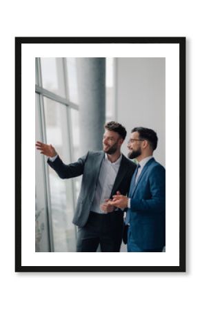 Two businessmen discussing strategy by office window
