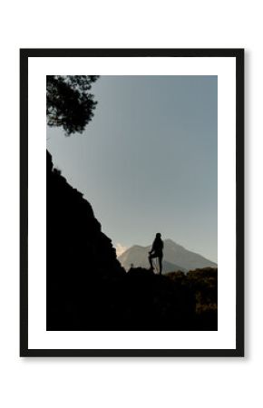 Great view of silhouette of woman with trekking poles against background of sky and mountains