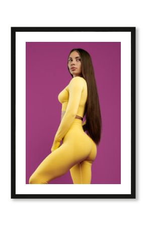 Pretty confident fit young brunette woman looking away over purple background. Power and motivation concept.
