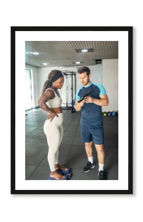 personal trainer weighing a client in the gym