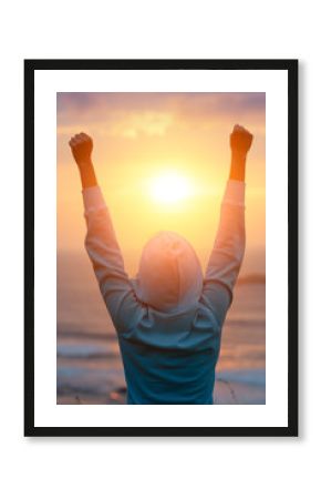 Rear view of motivated woman celebrating workout goals towards the sun. Morning healthy training success.