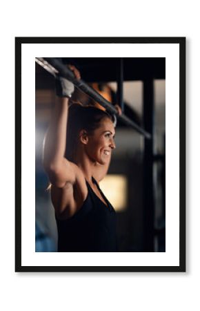 Young happy female athlete exercising in fitness center.