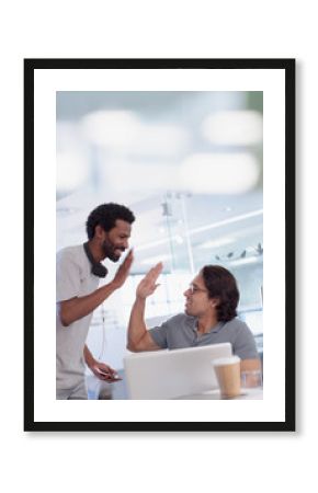 Excited creative businessmen high-fiving at laptop in office