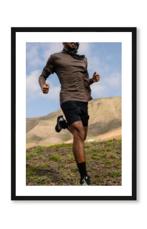 A trail runner moving along a rough path surrounded by rocks
