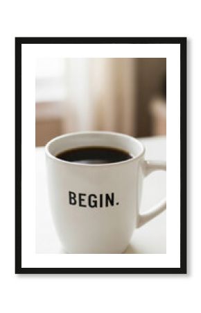 White mug filled with dark coffee, "BEGIN" inscribed on it, sits on a white surface against a blurred background, symbolizing new beginnings and motivation