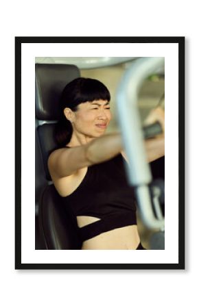 Determined Woman Using Exercise Machine in Gym for Strength Training Workout