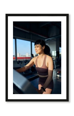 Woman Exercising on Treadmill in Gym During Daytime with Bright Lighting