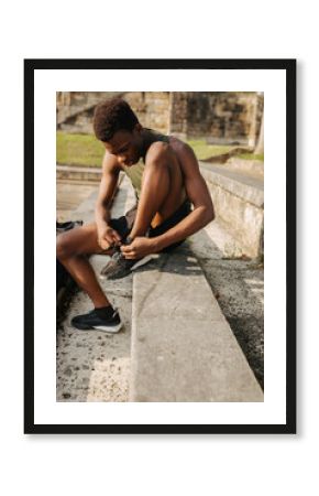 Athlete tying shoelaces while sitting on outdoor bench