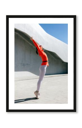 Joyful dancer in vibrant orange top leaps outdoor