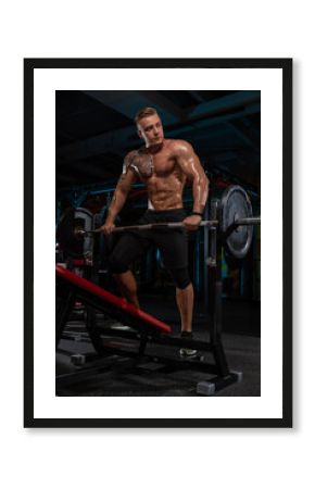 fit man with a strong physique is performing a weightlifting exercise in a gym. Sweat glistens on his skin as he engages in an intense workout surrounded by gym equipment.