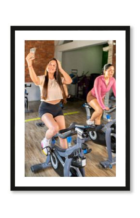 Women taking a selfie while cycling at the gym