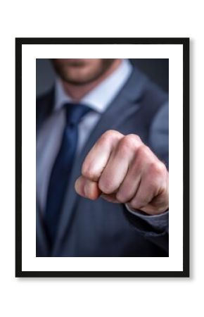 Confident businessman clenching his fist gently in a gesture of determination and motivation in a corporate environment.