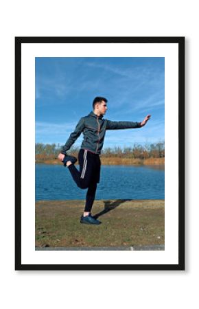 Man stretching outdoors beside lake on a sunny day