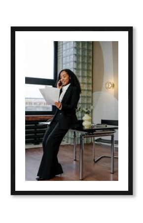 Businesswoman talking on phone while holding documents