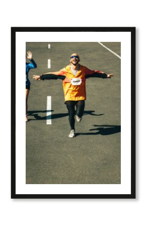 Male runner celebrating victory with arms outstretched on race day