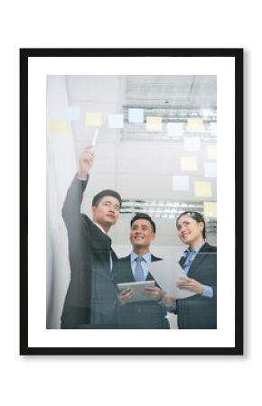 Businessman pointing at stickers with business ideas on glass wall