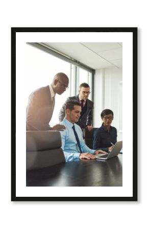 Group of co-workers looking at laptop on table