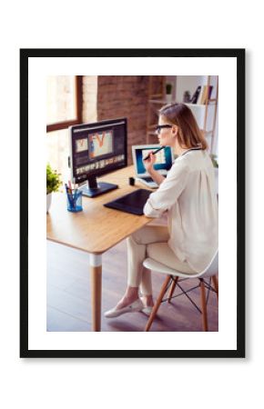 Vertical photo of attractive young photographer working with computer at the table and retouching with computer