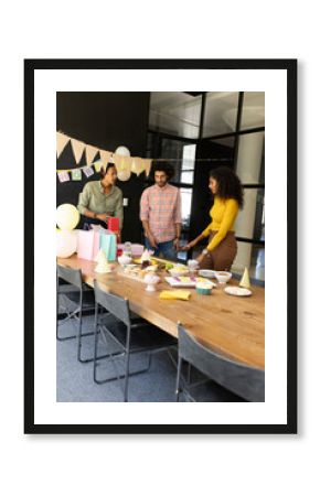 Colleagues preparing for office celebration with gifts and decorations on table