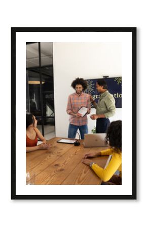 Diverse business team discussing project with tablet and laptop in modern office