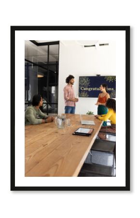 Celebrating success, team discussing achievements with congratulatory screen in office