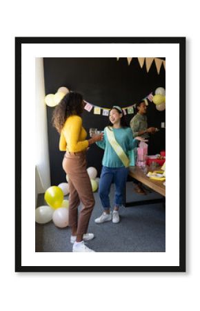 In office, diverse colleagues celebrating and chatting while holding drinks together
