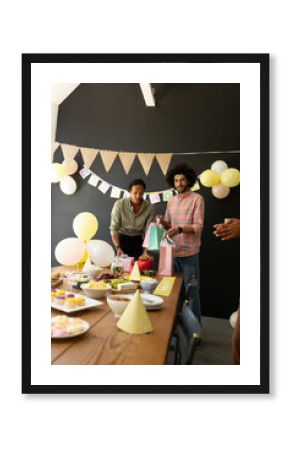 Colleagues preparing for office celebration, arranging gifts and snacks on table