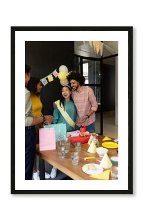 Celebrating at office, diverse colleagues enjoying party with gifts and decorations