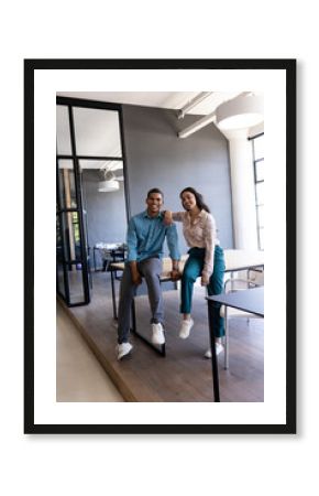 Smiling colleagues in modern office, sitting on desk, enjoying teamwork