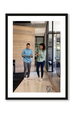 Colleagues in office hallway discussing project while checking smartphone together