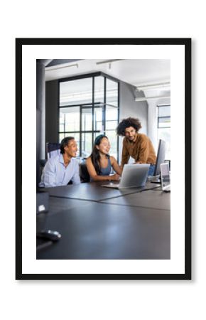 Diverse team collaborating on project using laptop in modern office space