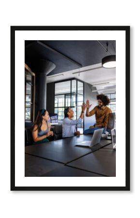 In modern office, diverse colleagues celebrating success with high five and smiles