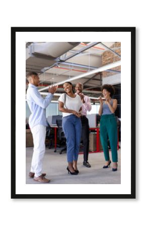 Colleagues celebrating success in modern office, smiling and applauding together