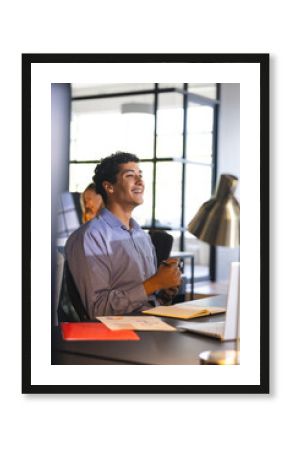 Smiling businessman in office holding smartphone, enjoying successful work moment
