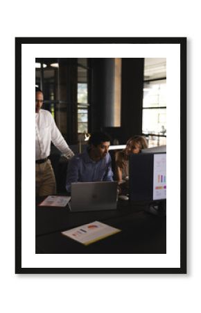 Collaborating on project, business professionals using laptop and charts in office