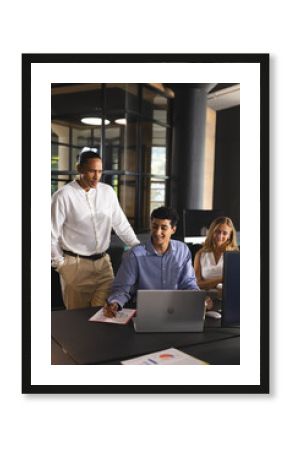 Collaborating in modern office, business professionals discussing project details on laptop