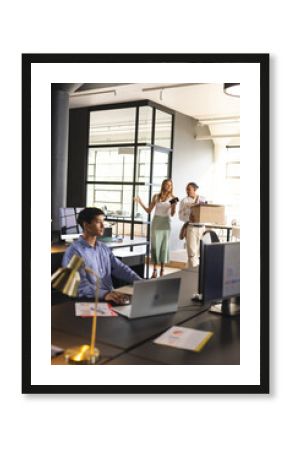 Discussing project, business professionals in office while colleague carries box
