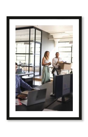 Colleagues welcoming new employee carrying box into modern office workspace