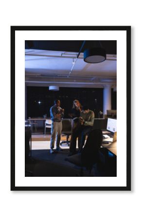 In office at night, business professionals reviewing documents and collaborating together