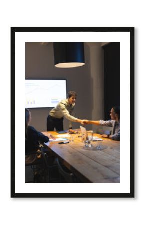 Business professionals shaking hands during meeting in modern conference room