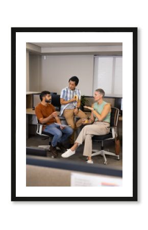 Discussing Diverse coworkers collaborating around ergonomic chairs in open-plan office, with paper